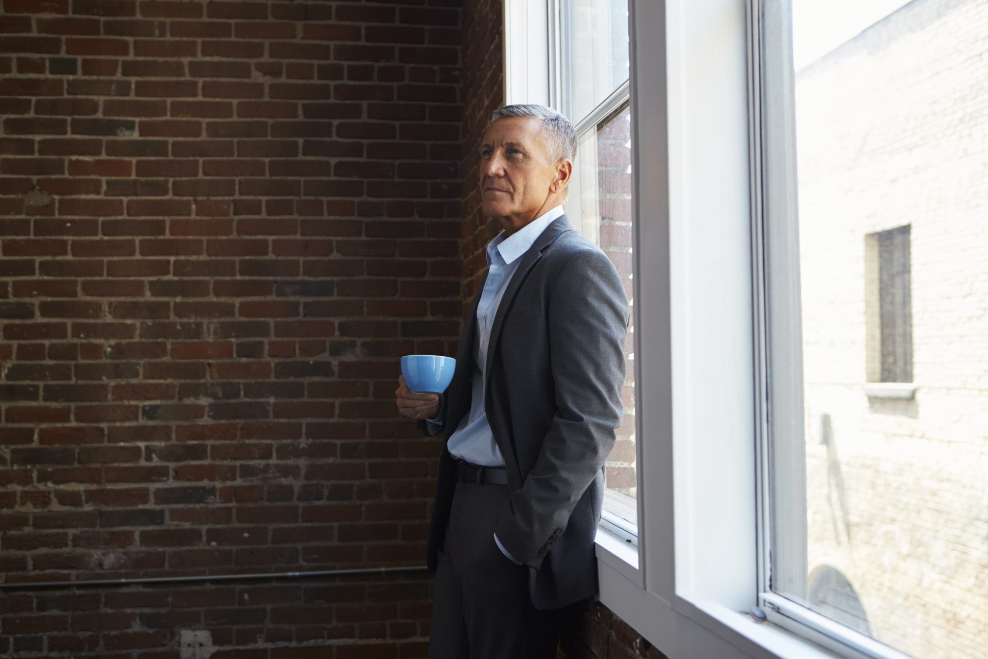 Unternehmer am Fenster, Kaffee in der Hand